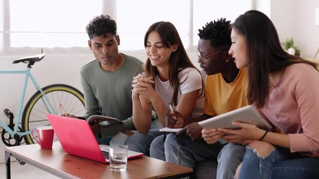 Multiethnic group of college student studying together preparing for exams. Millennial young people working together on laptop for university project. Education and youth concept.