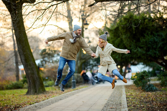 Affectionate smiling couple having fun jumping in the park