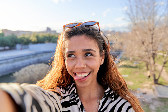 selfie of a latina woman making a funny face, sticking out her tongue and crossing her eyes. portrait of a young woman