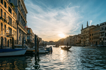 Gondolier on a gondola floats along a canal in Venice in the middle of ancient buildings on an early sunny morning. Beautiful romantic travel concept. Copyspac