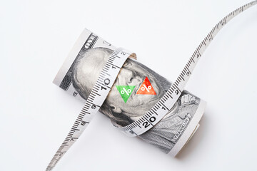 USD dollar banknote with green up arrow and red down arrow percentage was wrapped by a tape measure...
