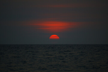 Fototapeta na wymiar sunset on the sea, dark sunset, red-orange semi-circle sun