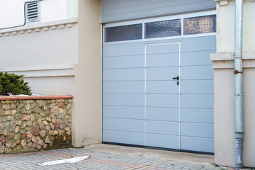 Large metal garage doors. Modern automatic garage door. Closed roller gates. Safe storage of the car.