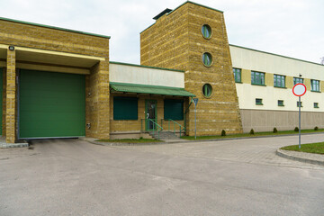 A large modern garage made of beige brick and green roller gates. Video surveillance system at the entrance to the garage. Safe conditions for storing cars and property.