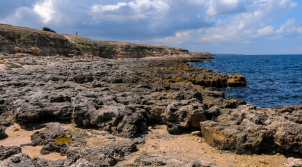 Fototapeta na wymiar Flat rocky shore with many littoral puddles rich in life, in the eastern Crimea, Black Sea
