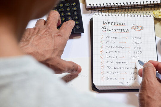 Man calculating wedding expenses on notepad. Selective focus.