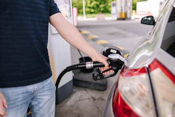 Man refueling the car at a gas station. Close-up of driver hand pumping gasoline car with fuel at the refuel station.