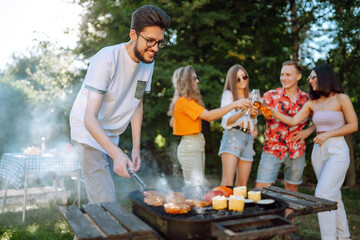 Сompany of people having bbq party on in summer park. Friends grill meat, have fun, relax. Сoncept of lifestyle, holidays, weekends and leisure. Picnic and barbecue.