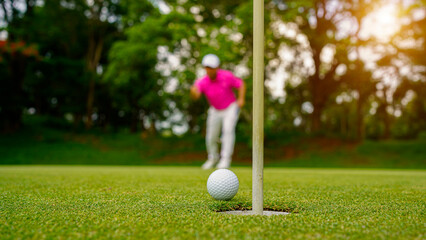 Fototapeta na wymiar Golfer putting ball on the green golf, lens flare on sun set evening time.