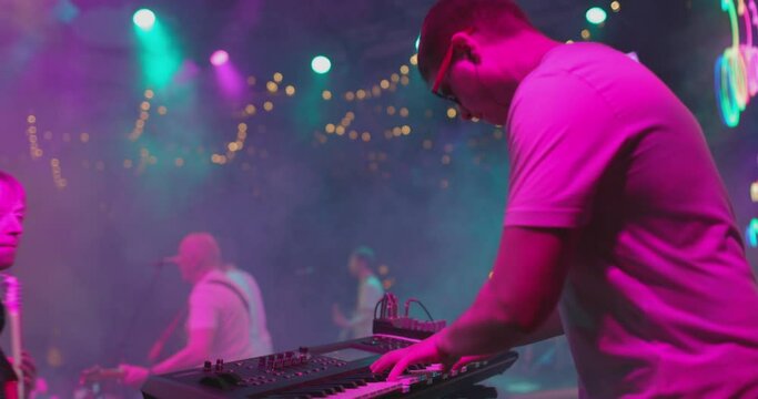 Men play an electric synthesizer in close-up. Fingers press keys. Slow motion