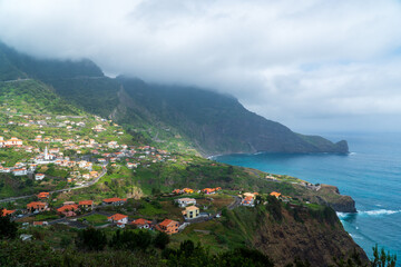 Amazing view of the village Porto da Cruz in Madeira island, Portugal. Small city in the hills by the coast of the Atlantic ocean. Dominant rock by the ocean. Portuguese tourist destination.