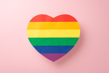 A top-view image of LGBT support symbol, big rainbow colored heart, displayed on a pastel pink background with an open space for text or advertising