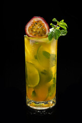 Closeup glass of Mojito with passion fruit ( maracuya ) lime and green leaf mint isolated on black...