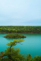 Obraz premium A small island with trees in Harpswell Cove over Cliff Trail, a hiking path landscape. Tranquil Maine coastal road seascape near Casco Bay and Orr’s Island on a foggy morning. 