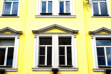Fototapeta na wymiar old yellow house facade in classical style. Decorated window frames