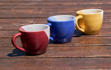 Tea time. Family time. Three multi colored cups on a wooden brown table 