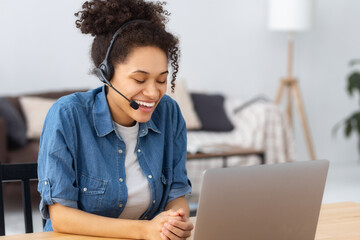 Smiling young African American modern woman entrepreneur or office worker in headset working,...