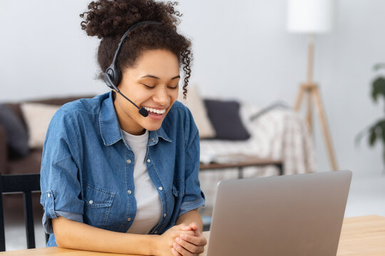 Smiling young African American modern woman entrepreneur or office worker in headset working, having a video conference meeting with employees or a client, advising