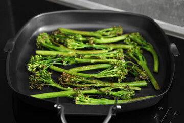 Grill pan with tasty cooked broccolini on cooktop, closeup