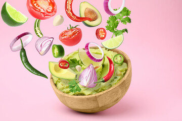 Delicious guacamole with flying ingredients on pink background