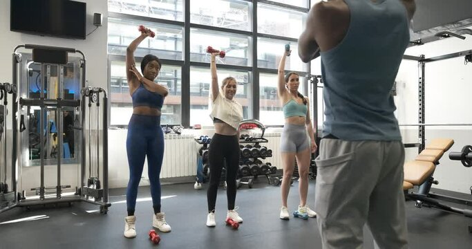 Group of multiracial people lifting dumbbells in fitness studio together