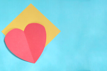 Red paper heart and yellow card on blue background. Valentines day card with copy space