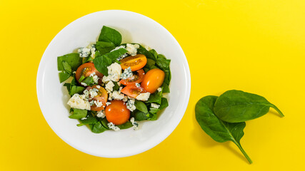 Salad from baby spinach leaves with tomatoes and blue cheese