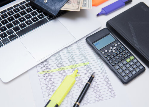 flat lay photo showing calculator, financial figures, highlighter and laptop. Concept showing financial analysis or accounting