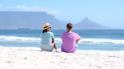 Fototapeta premium Bloubergstrand Cape Town South Africa on a bright summer day, couple on the beach, men and women chilling on the beach during vacation in Cape Town South Africa