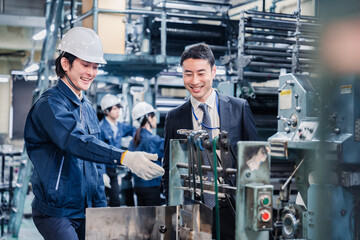 機械の前で話をする営業マンと労働者