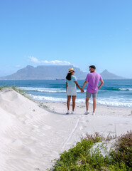 Bloubergstrand Cape Town South Africa on a bright summer day, Blouberg beach, with powder-soft white sand, and blue ocean. couple on the beach, men and women chilling on the beach
