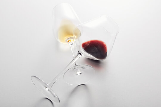 Wineglasses with red, white wine lying with stems crossed.