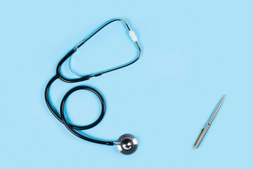 Stethoscope on light blue background, top view. Space for text