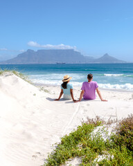 Fototapeta premium Bloubergstrand Cape Town South Africa on a bright summer day, couple on the beach, men and women chilling on the beach during vacation in Cape Town South Africa