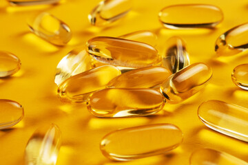 Fish oil capsules with omega 3 and vitamin D on yellow background