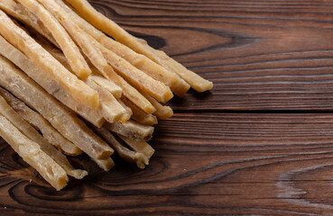 Close-up of dried salted tuna stripes on wooden background. Beer snacks, restaurant menu, salty seafood