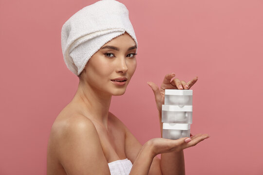 Asian lady holds three empty cosmetic jars on palm.