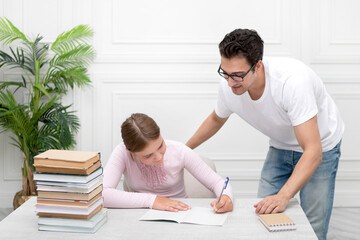 Fototapeta na wymiar Father and daughter studying together at home. He explaining lesson and she listening him carefully. Stack of books, laptop and exercise book on the desk. Online education concept
