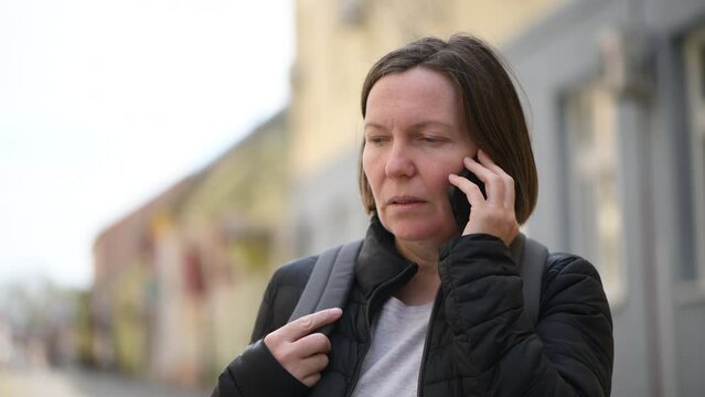 Mid-adult brunette female talking on mobile phone at the street