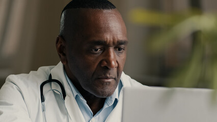 Obraz premium African man doctor therapist psychotherapist general practitioner work at hospital use laptop male therapist nurse giving distant online consultation on computer to patient chatting in medical chat
