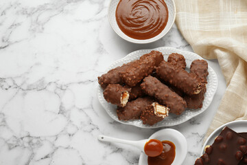 Tasty chocolate bars with caramel on white marble table, flat lay. Space for text