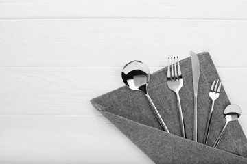 Stylish shiny cutlery set on white wooden table, flat lay. Space for text