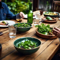 Family lunch around wooden table in green patio Focus on handmade porcelain green plates emerald green bowls and salad bowl in dark shinny emerald green There is a salad