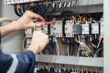 Electrician engineer work tester measuring voltage and current of power electric line in electical cabinet control , concept check the operation of the electrical system .