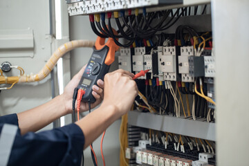 Electrician engineer work tester measuring voltage and current of power electric line in electical cabinet control , concept check the operation of the electrical system . - obrazy, fototapety, plakaty