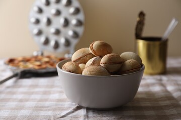 Bowl of delicious walnut shaped cookies with condensed milk on checkered tablecloth