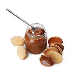 Jar with boiled condensed milk, spoon, cooked dough and walnut shaped cookies on white background