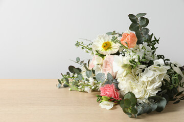 Bouquet of beautiful flowers on wooden table against white wall. Space for text - obrazy, fototapety, plakaty