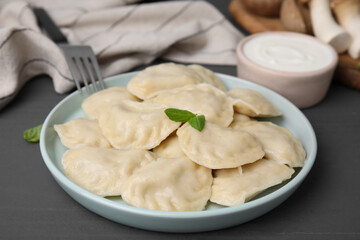 Plate of delicious dumplings (varenyky) on grey wooden table, closeup