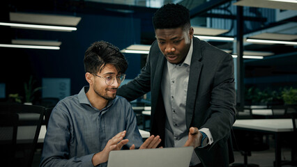 Male businessmen colleagues work with computer corporate teamwork develop digital business presentation two multiracial men arabian guy and african man discussing project software co-working at office